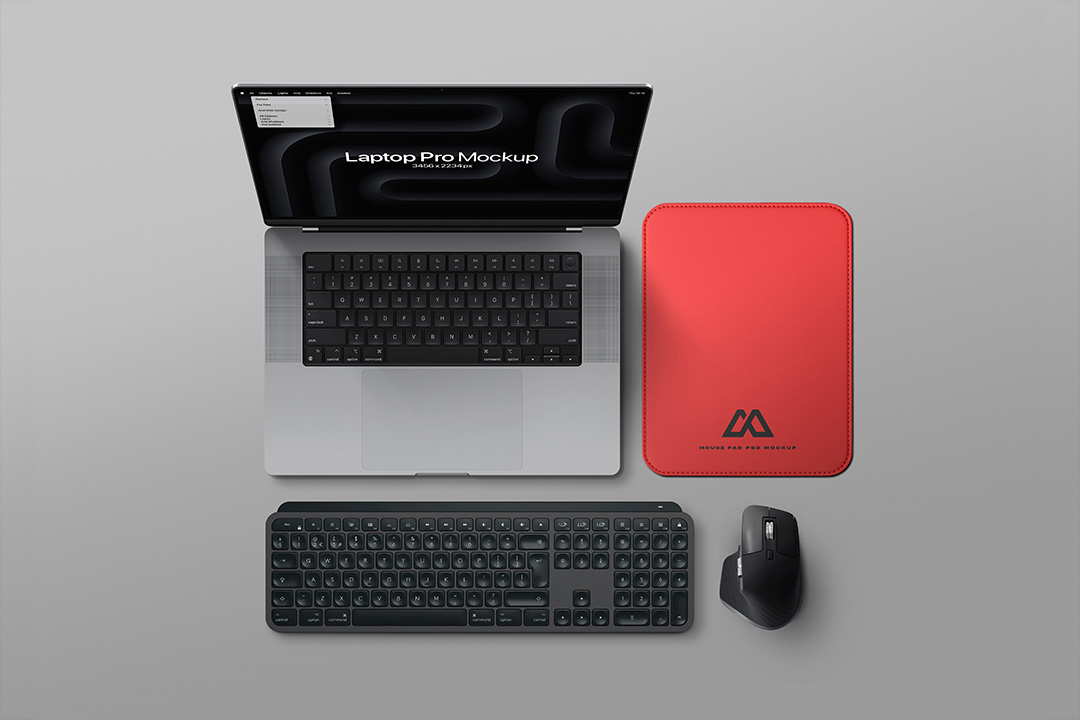A flat-lay arrangement showing a MacBook Pro, a red mouse pad, a keyboard, and a mouse on a grey background.