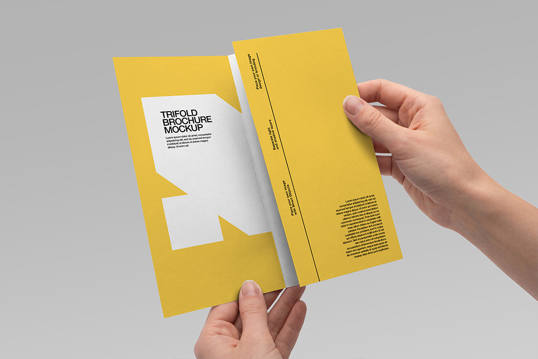 Two hands holding an open trifold brochure mockup showing inner spread with yellow panels and Smart Object placeholders on grey