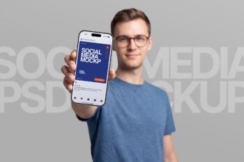 Hand holding Instagram post mockup with a smiling man in glasses showing an iPhone on grey background