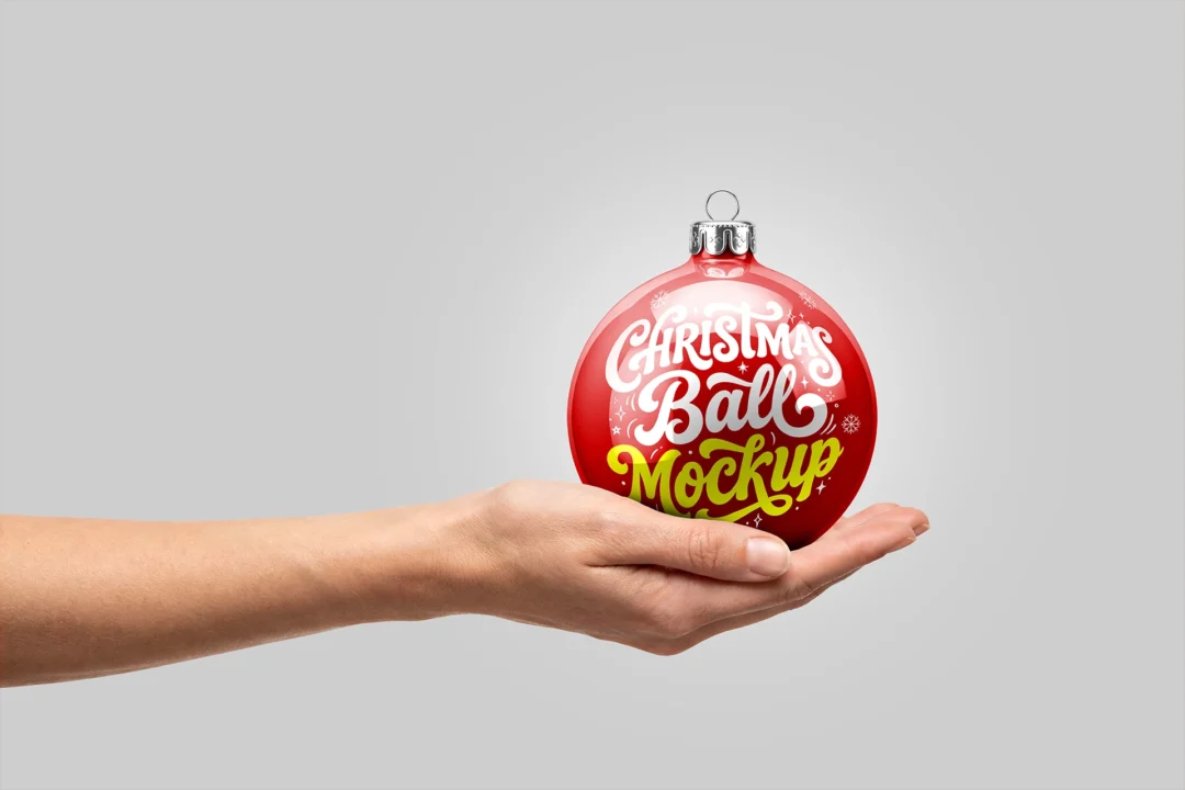 Christmas ornament mockup in hand, glossy red ball with silver cap resting on an open palm over gray