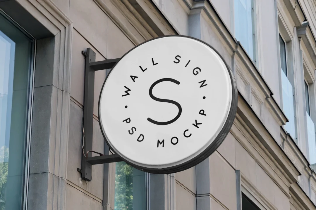 Wall sign mockup set round white hanging sign on a dark metal bracket against a beige stone building facade
